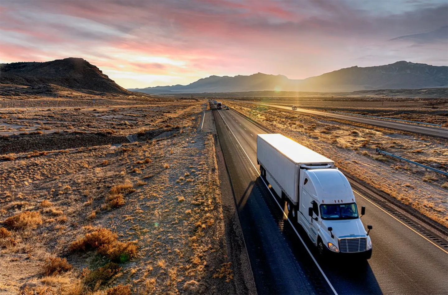 A truck driving on a street in an arid, rural environment